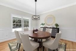 dining space featuring hardwood / wood-style floors, ornamental molding, and an inviting chandelier