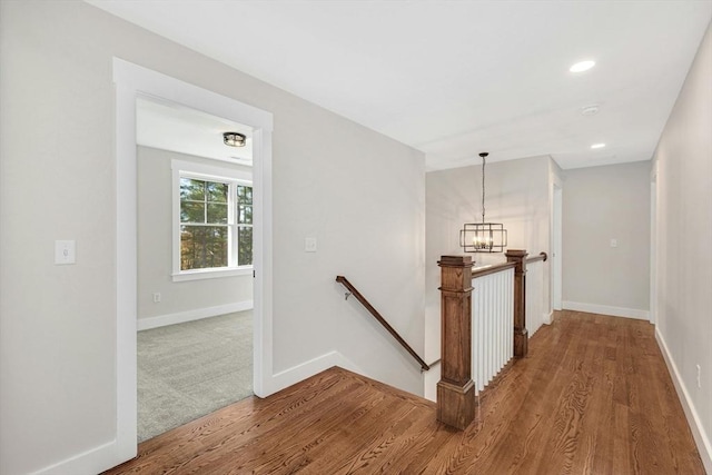 stairs featuring hardwood / wood-style flooring and an inviting chandelier