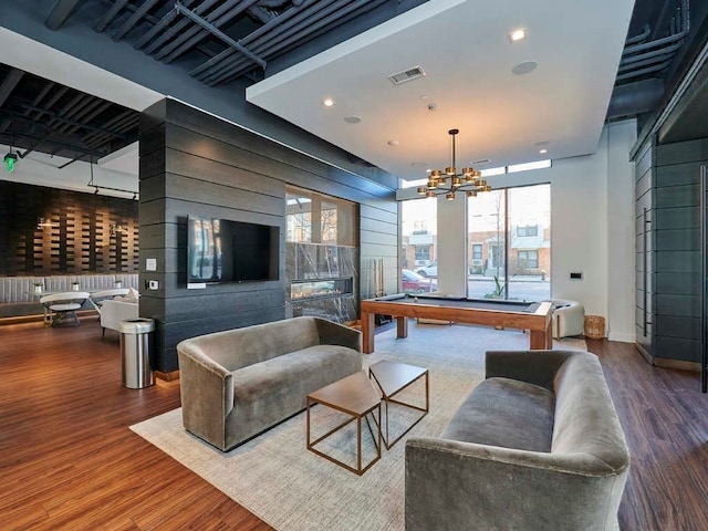 living room featuring a notable chandelier, pool table, and dark wood-type flooring