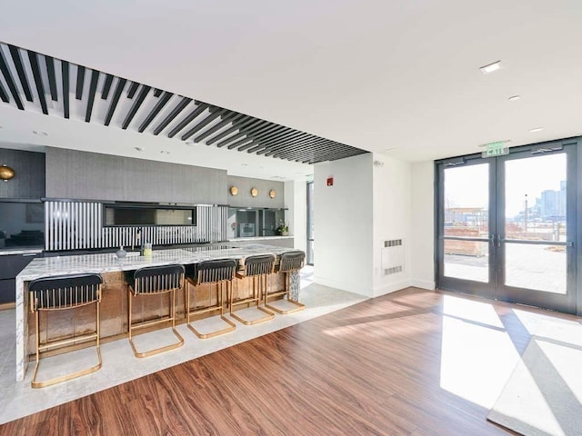 kitchen with light hardwood / wood-style floors, french doors, tasteful backsplash, a center island, and a breakfast bar area