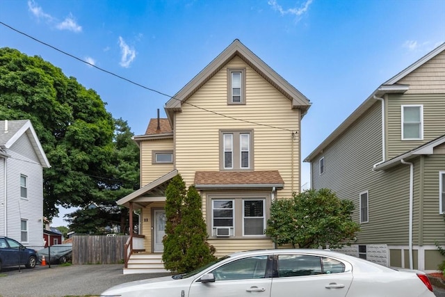 traditional home with a shingled roof and fence