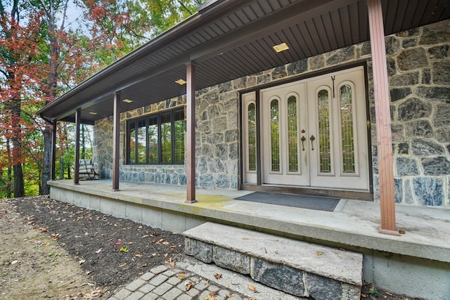 view of exterior entry with covered porch and french doors