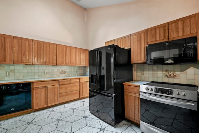 kitchen with a towering ceiling, decorative backsplash, and black appliances