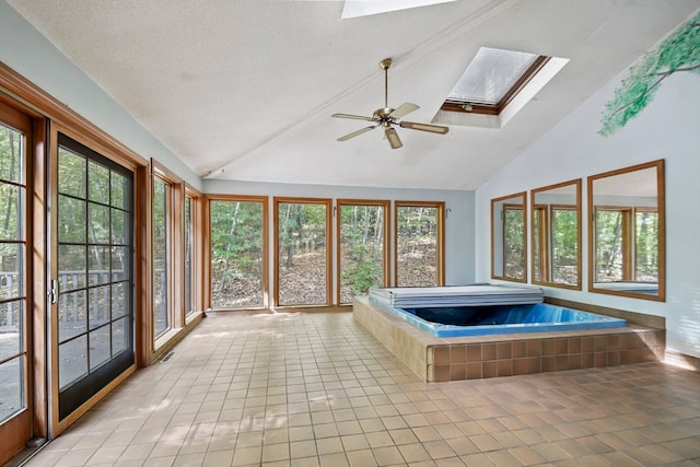 unfurnished sunroom featuring ceiling fan, lofted ceiling with skylight, and a hot tub