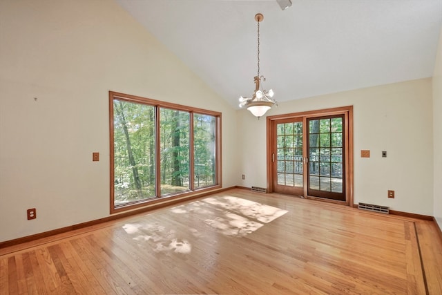 unfurnished room featuring wood-type flooring, high vaulted ceiling, and an inviting chandelier