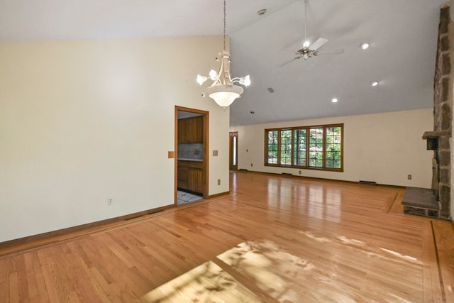 unfurnished living room featuring ceiling fan with notable chandelier, high vaulted ceiling, and light hardwood / wood-style flooring