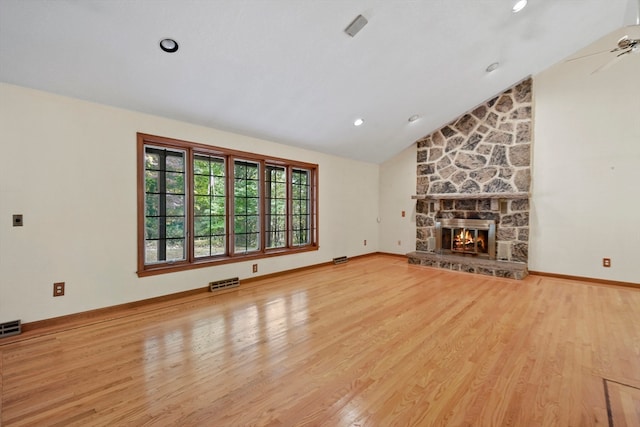 unfurnished living room featuring ceiling fan, a stone fireplace, hardwood / wood-style flooring, and high vaulted ceiling