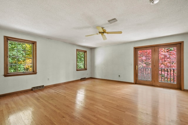 empty room featuring ceiling fan, light wood-type flooring, and a textured ceiling