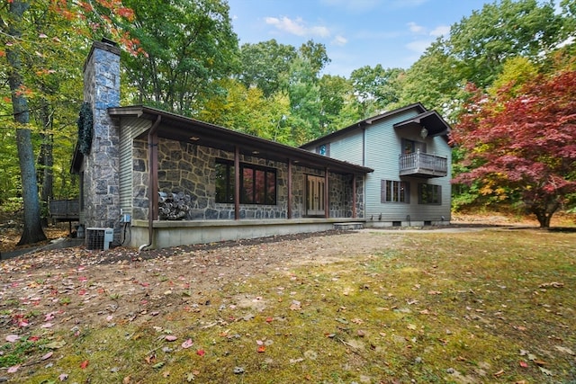 view of property exterior featuring cooling unit, a balcony, and a lawn