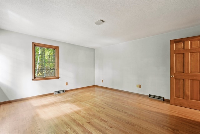 empty room with a textured ceiling and light wood-type flooring