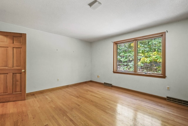 spare room featuring light hardwood / wood-style flooring and a textured ceiling