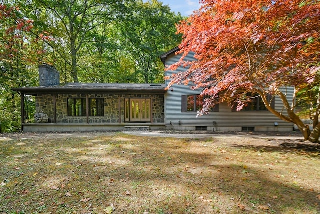 rear view of property featuring a lawn