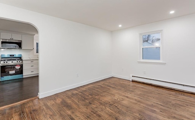 empty room with dark wood-type flooring and a baseboard heating unit