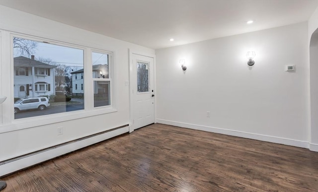 unfurnished room featuring dark wood-type flooring and a baseboard heating unit