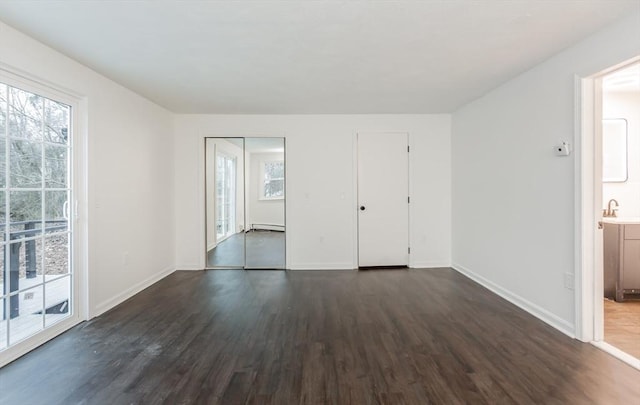 spare room featuring dark hardwood / wood-style floors, sink, and a baseboard radiator