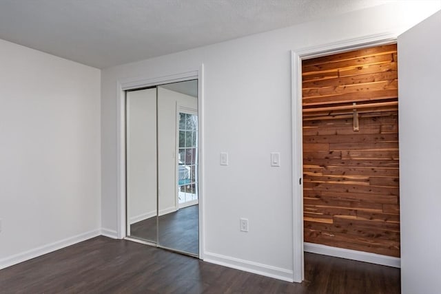 unfurnished bedroom featuring a textured ceiling, a closet, and dark wood-type flooring