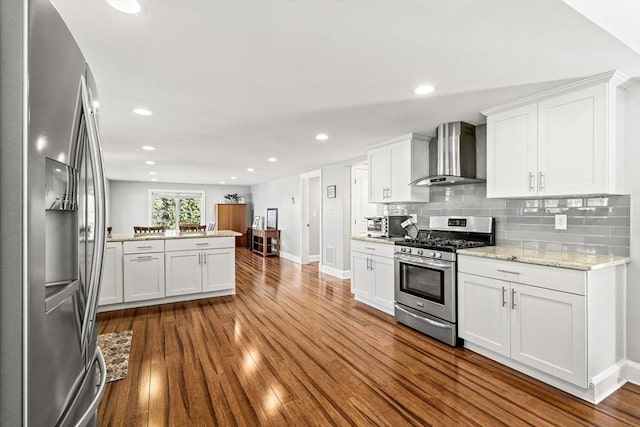 kitchen with baseboards, appliances with stainless steel finishes, dark wood finished floors, and wall chimney exhaust hood