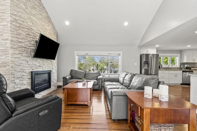 living area with recessed lighting, high vaulted ceiling, wood finished floors, and a fireplace