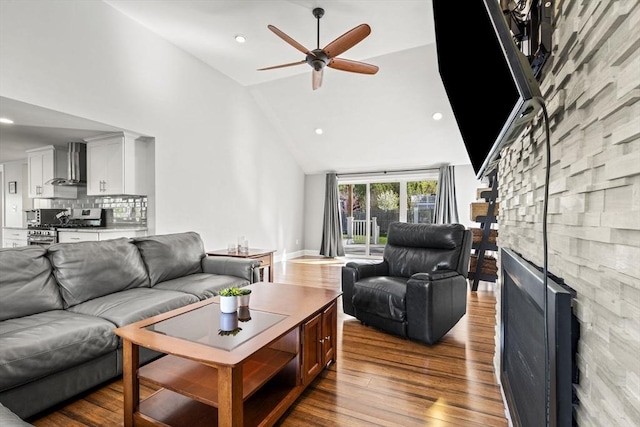 living room with ceiling fan, a fireplace, wood finished floors, high vaulted ceiling, and recessed lighting