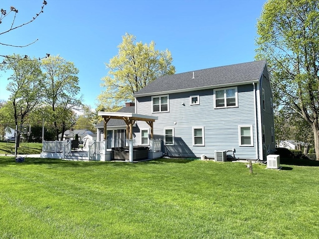 rear view of house featuring a hot tub, a lawn, a wooden deck, and a chimney