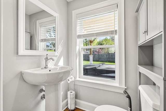 half bath featuring baseboards and toilet