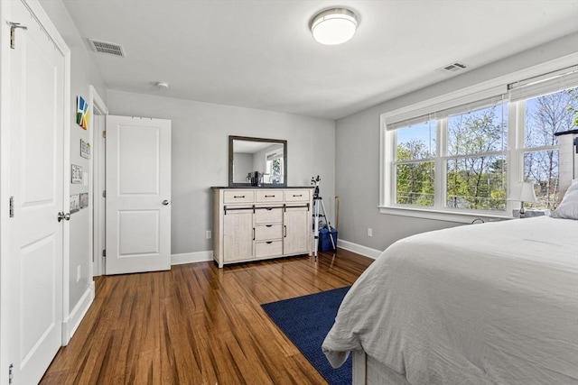 bedroom with visible vents, baseboards, and dark wood-style flooring