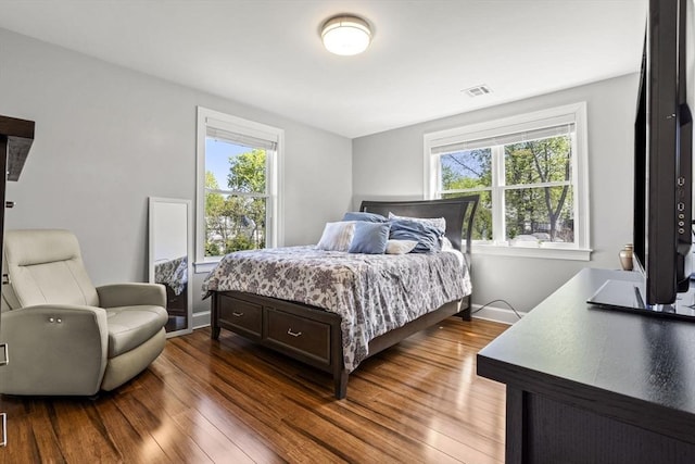 bedroom with visible vents, multiple windows, and dark wood-type flooring