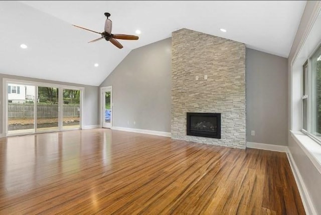 unfurnished living room featuring wood finished floors, a fireplace, baseboards, ceiling fan, and high vaulted ceiling