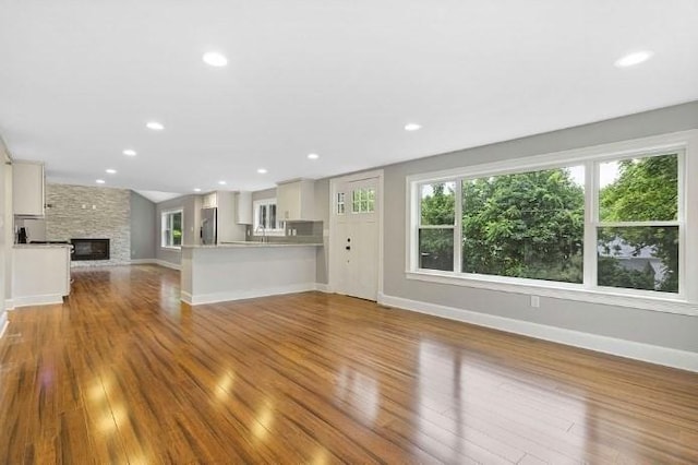 unfurnished living room with baseboards, recessed lighting, wood finished floors, and a fireplace