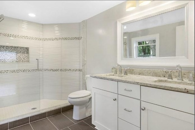 full bath with a sink, tile patterned flooring, a shower stall, and toilet