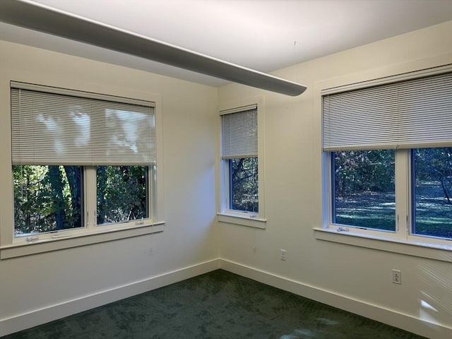 spare room with dark carpet and baseboards