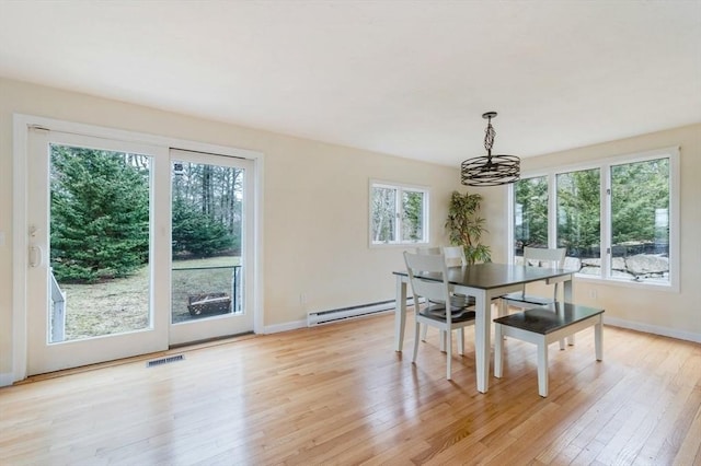 dining area with a chandelier, light wood finished floors, a baseboard heating unit, and baseboards