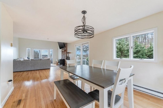 dining room with a chandelier, light wood-style floors, a baseboard heating unit, and baseboards