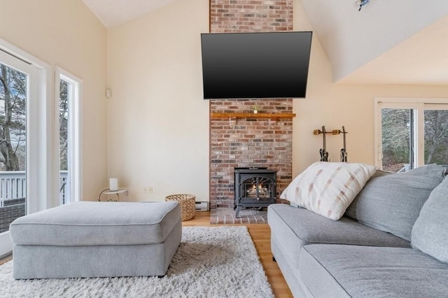 living area with a wood stove, high vaulted ceiling, and light wood finished floors