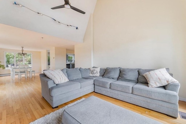 living area with high vaulted ceiling, a ceiling fan, and light wood-style floors