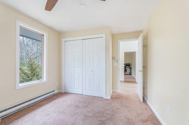 unfurnished bedroom featuring a closet, carpet, multiple windows, and a baseboard heating unit