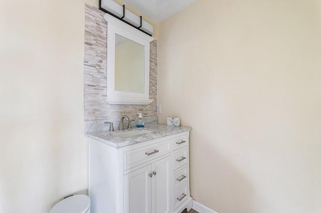 bathroom with toilet, vanity, baseboards, and backsplash