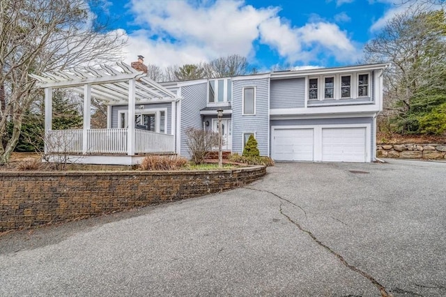 view of front of house with an attached garage, driveway, and a chimney