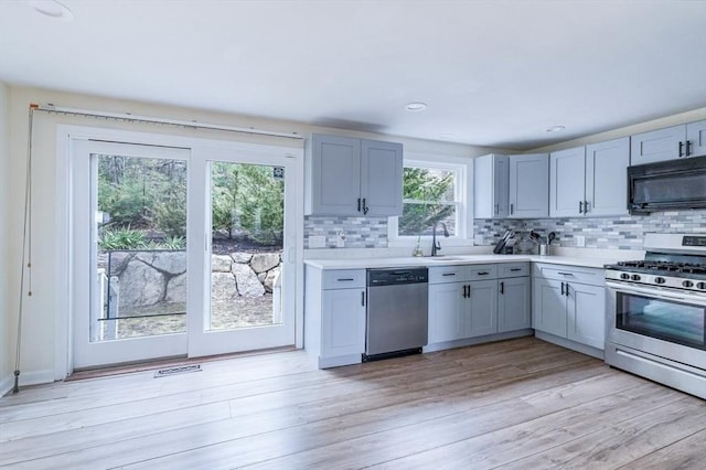 kitchen with a sink, light countertops, appliances with stainless steel finishes, and decorative backsplash