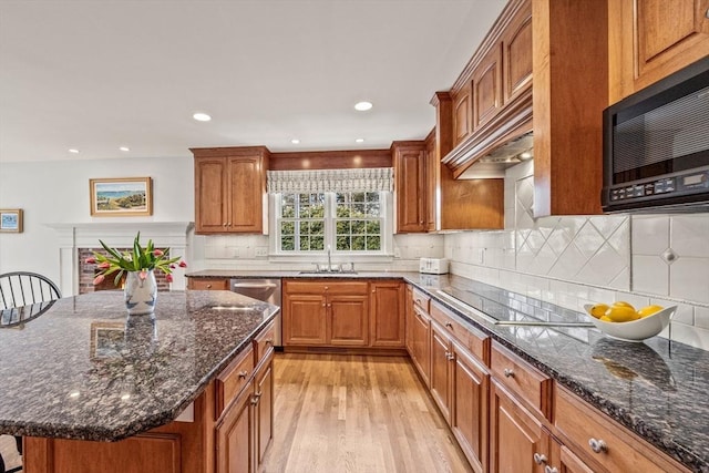 kitchen with dark stone countertops, a center island, sink, and black appliances