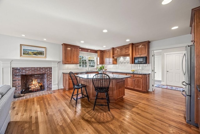 kitchen with stainless steel fridge, a breakfast bar, a center island, tasteful backsplash, and wood-type flooring