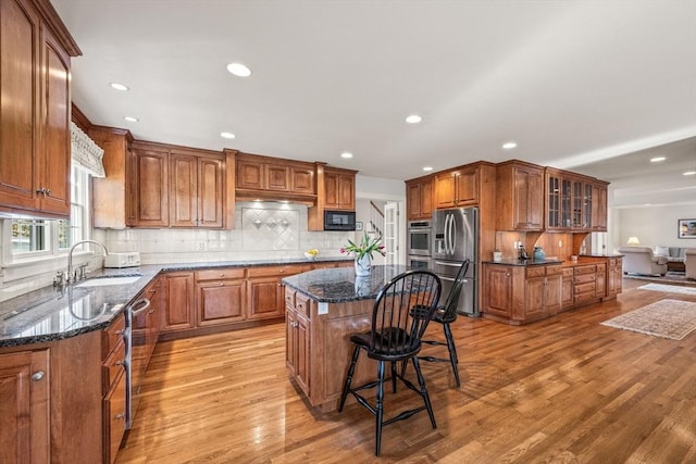 kitchen featuring appliances with stainless steel finishes, a center island, sink, and dark stone counters