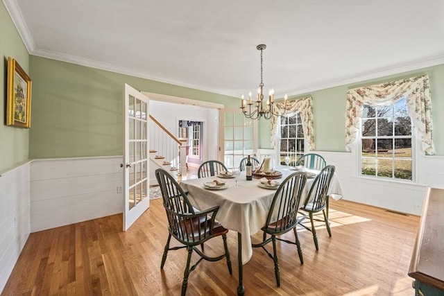 dining room featuring crown molding, a chandelier, light hardwood / wood-style floors, and french doors