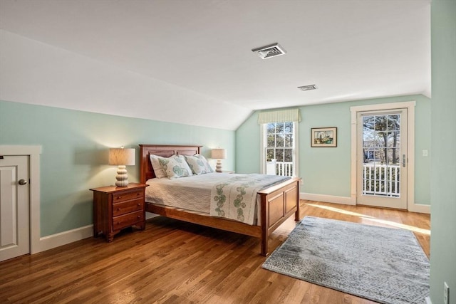 bedroom with hardwood / wood-style flooring, access to exterior, and vaulted ceiling