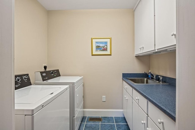 clothes washing area with cabinets, sink, washer and dryer, and dark tile patterned floors