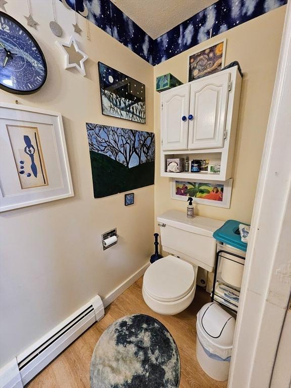 12 Sutton Ct Unit 12, Amherst, MA 01002 - bathroom featuring a baseboard heating unit, wood finished floors, toilet, and baseboards