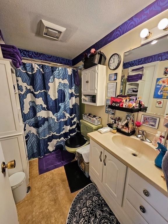 12 Sutton Ct Unit 12, Amherst, MA 01002 - full bathroom featuring a textured ceiling, tile patterned floors, vanity, toilet, and a shower with curtain