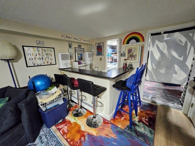 12 Sutton Ct Unit 12, Amherst, MA 01002 - kitchen with wood finished floors, a breakfast bar, and dark countertops