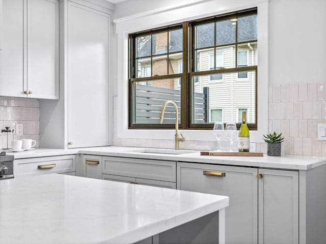 kitchen featuring decorative backsplash, light stone countertops, and sink