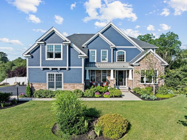 craftsman-style house with stone siding, a standing seam roof, a porch, and a front yard